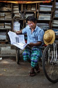 Full length of man reading newspaper at market