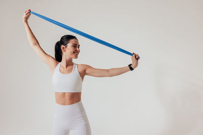 Young woman exercising against white background