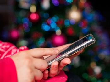 Cropped image of woman using mobile phone during christmas