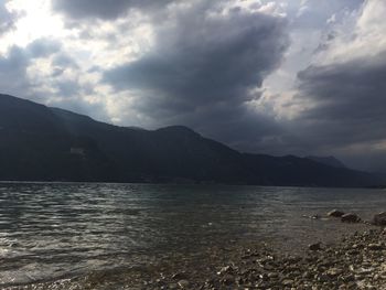 Scenic view of sea and mountains against cloudy sky