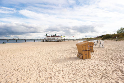 Hooded chairs on beach against sky