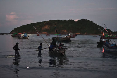 People on boats in sea against sky