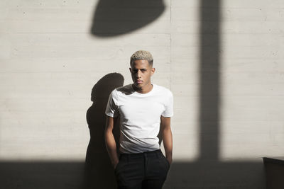 Portrait of young man standing against wall