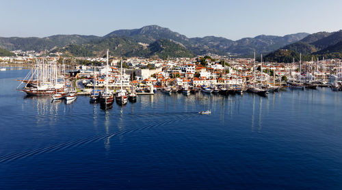 High angle view of sailboats in sea by buildings against sky