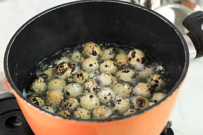 Boiled quail egg in orange dutch oven pan, cooking backstage in the kitchen.