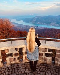 Rear view of woman at observation point against river and mountains