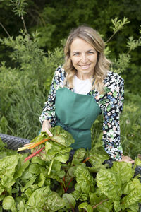Portrait of smiling young woman standing against plants