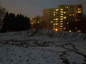 Illuminated buildings in city at night during winter