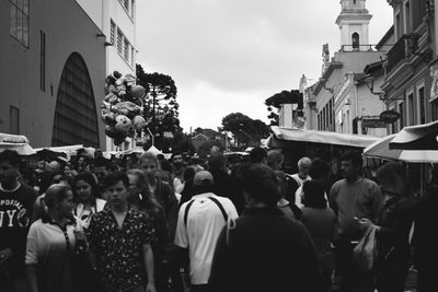 People walking on street in city against sky