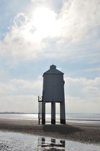 Water tower on beach against sky