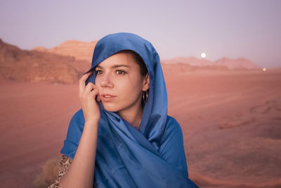 Portrait of beautiful young woman in desert against sky