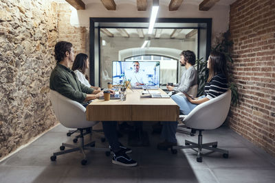 Businessman explaining colleagues on video call in meeting at creative office