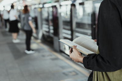 Midsection of woman reading book in city