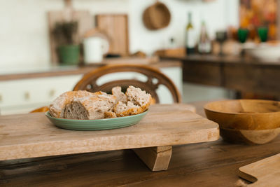 Pieces of black bread lie in a turquoise plate on a wooden stand on the dining table