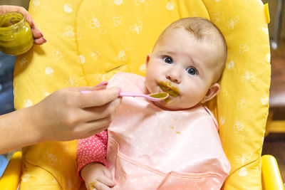 Mother feeding cute baby girl at home