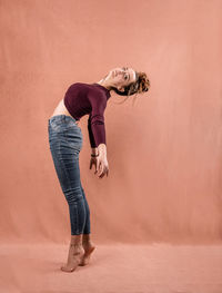 Full length portrait of woman standing against wall