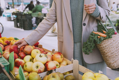 Hand of woman buying fresh apples at market