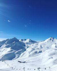 Scenic view of snow covered mountains against blue sky