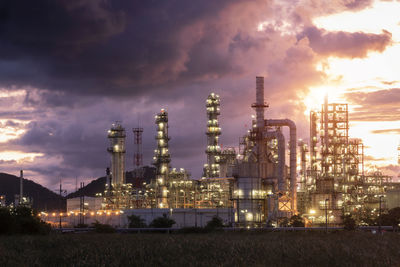 Illuminated factory against sky at sunset