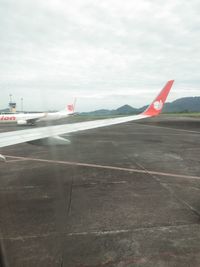 Airplane on airport runway against sky