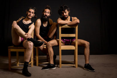 Portrait of young men sitting on chairs