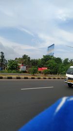 Road by trees against sky in city