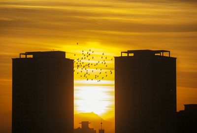 Silhouette buildings against sky during sunset