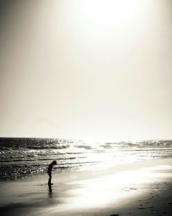 Silhouette man standing on beach against sky during sunset