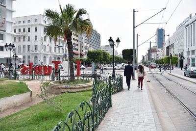 Rear view of people walking on street amidst buildings in city