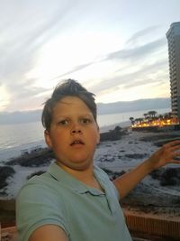 Portrait of man standing at beach against sky