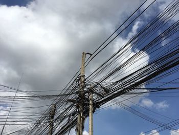 Low angle view of electricity pylon against cloudy sky