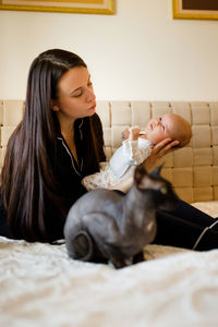 Mother with baby sitting on bed at home