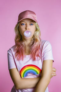 Portrait of cool young woman with bubble gum in front of pink background