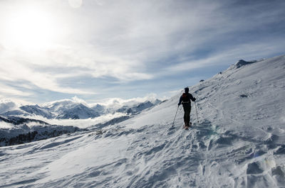 Rear view of woman skiing on snowcapped mountain against sky