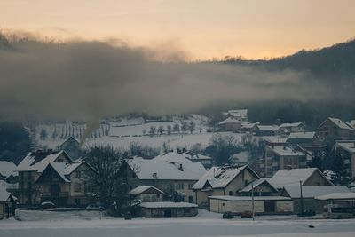 Houses by snow covered mountains against sky