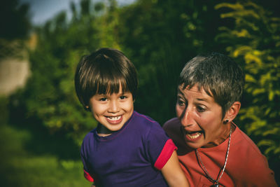 Portrait of happy grandson with grandmother against trees