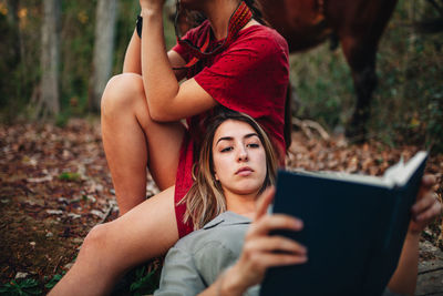 Low section of woman using phone while sitting on land