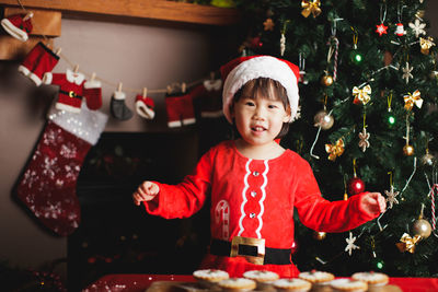 Portrait of smiling girl standing by cookies on table at home during christmas
