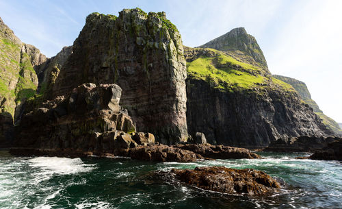 Rock formation by sea against sky