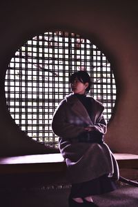 Rear view of woman standing by window