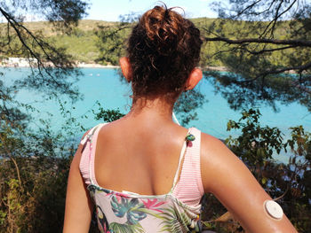 Girl with diabetes looks at the turquoise sea. on right arm is placed white sensor for  cgm devise.