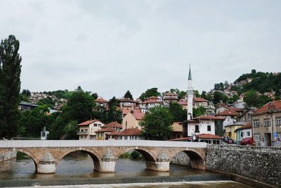 Bridge over river in town against sky