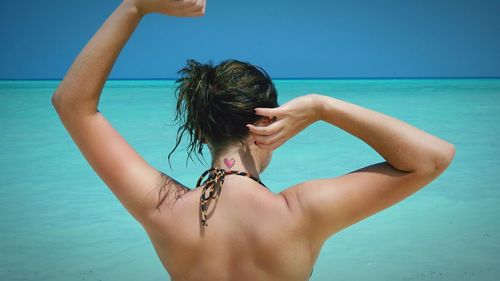 Rear view of woman at sea shore against sky