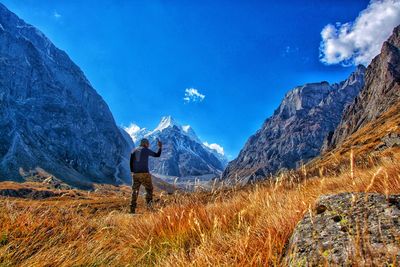 Man standing on mountain against blue sky