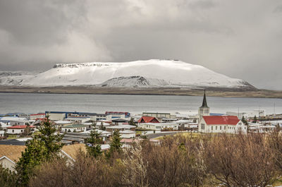 View from the hills towards the town and church, with the fjord and snow-covered mountains 