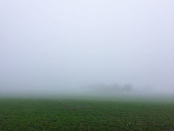 Scenic view of field in foggy weather against sky