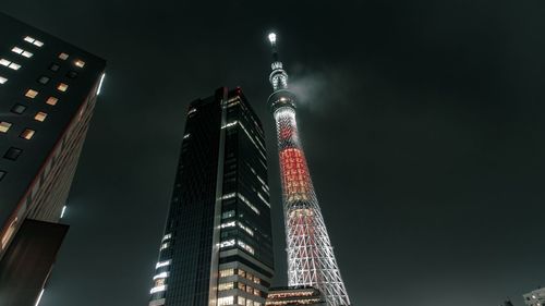 Low angle view of illuminated buildings against sky at night