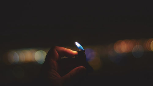 Close-up of hand holding lit candle