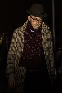 Midsection of man wearing hat standing against black background