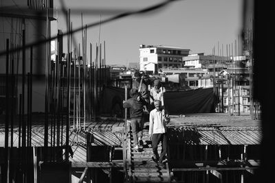 People walking by building in city against sky